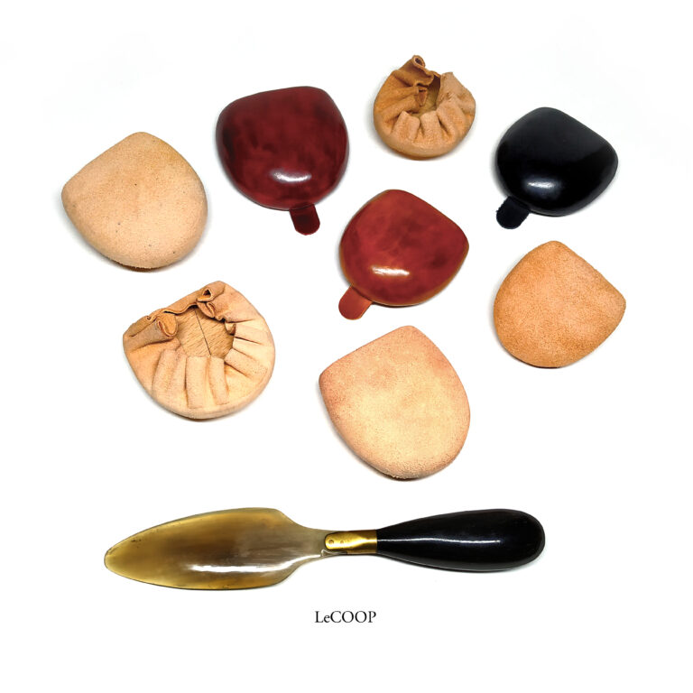 Monederos de cuero moldeado en natural, granate y negro junto a un calzador
