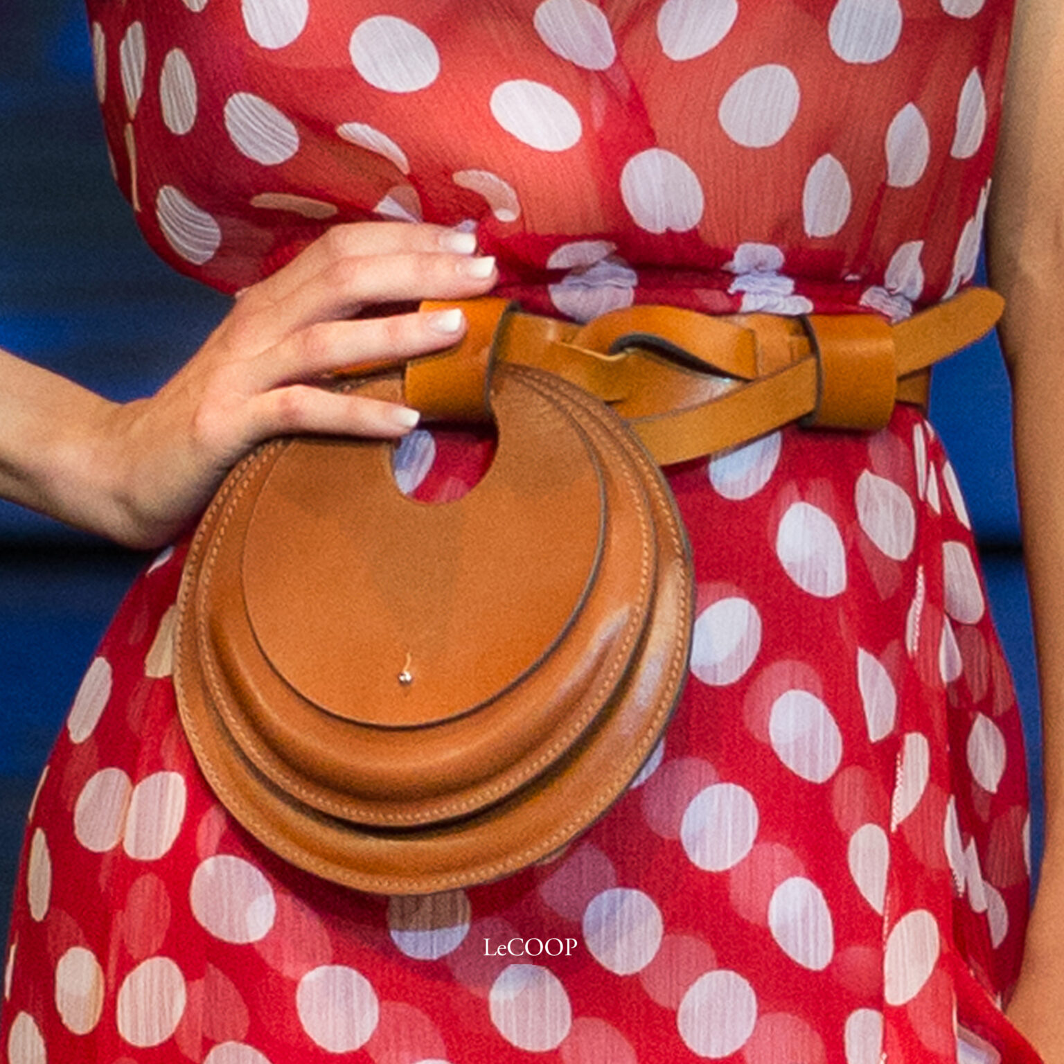 Modelo con vestido rojo de lunares y cinturón de cuero anudado con bolso circular