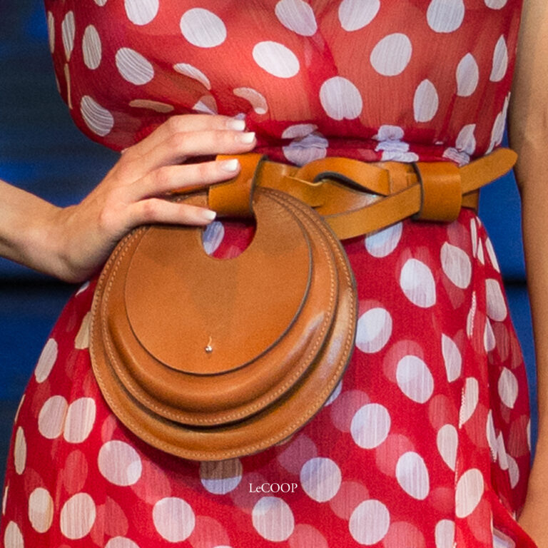 Modelo con vestido rojo de lunares y cinturón de cuero anudado con bolso circular