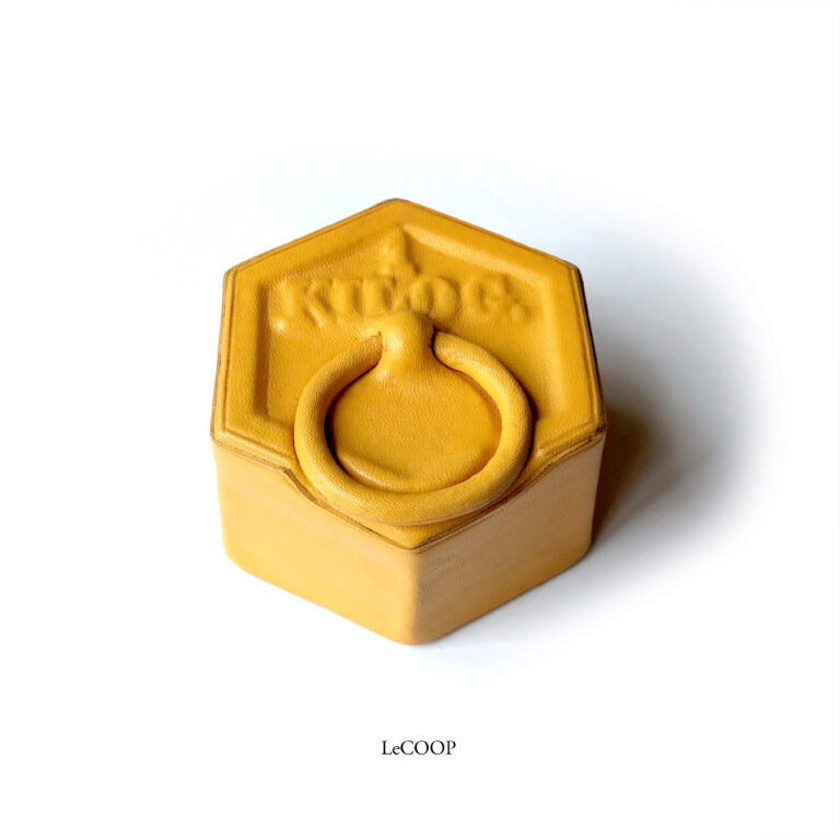 Pesa hexagonal de un kilo forrada en cuero amarillo, con la inscripción y la anilla en relieve