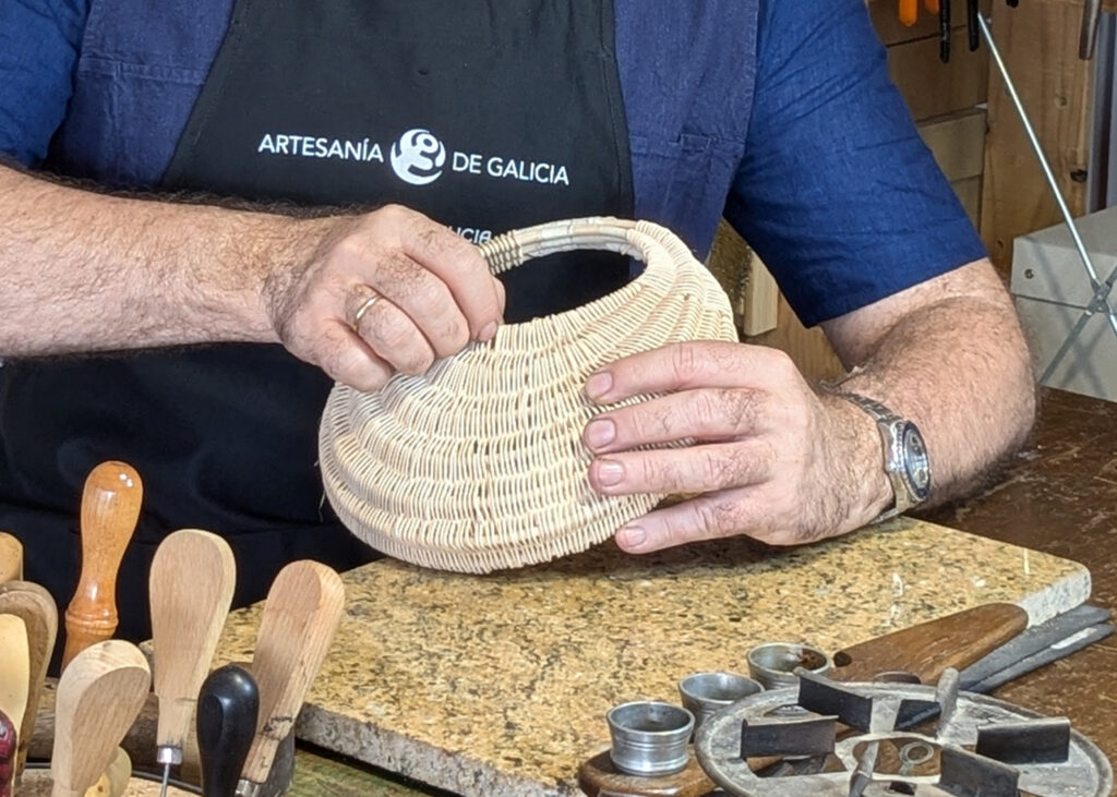 Víctor Montero sujeta un bolso cesta de fibra natural sobre el banco de trabajo