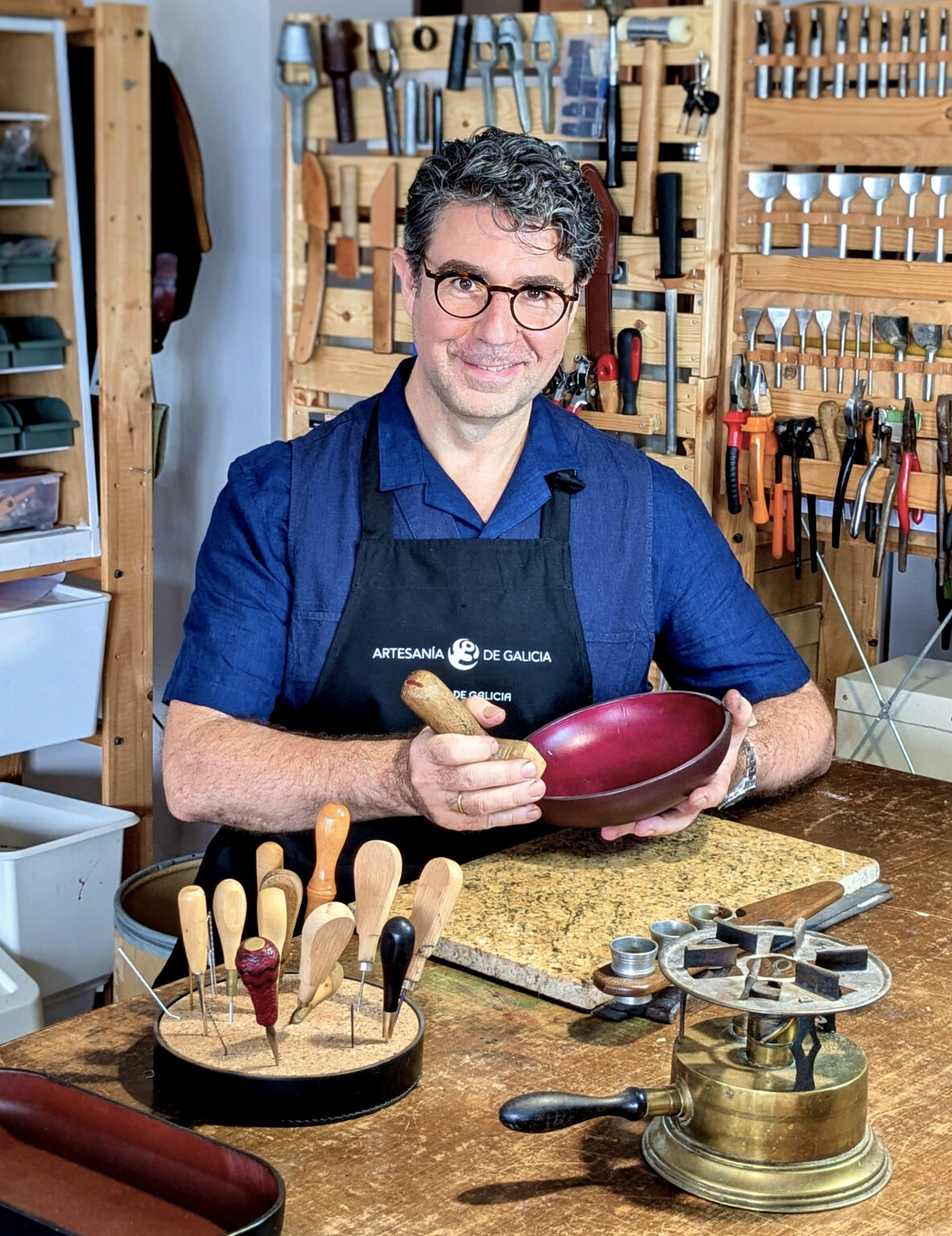 Víctor Montero sonríe en su taller de Lugo con un cuenco de cuero granate en las manos