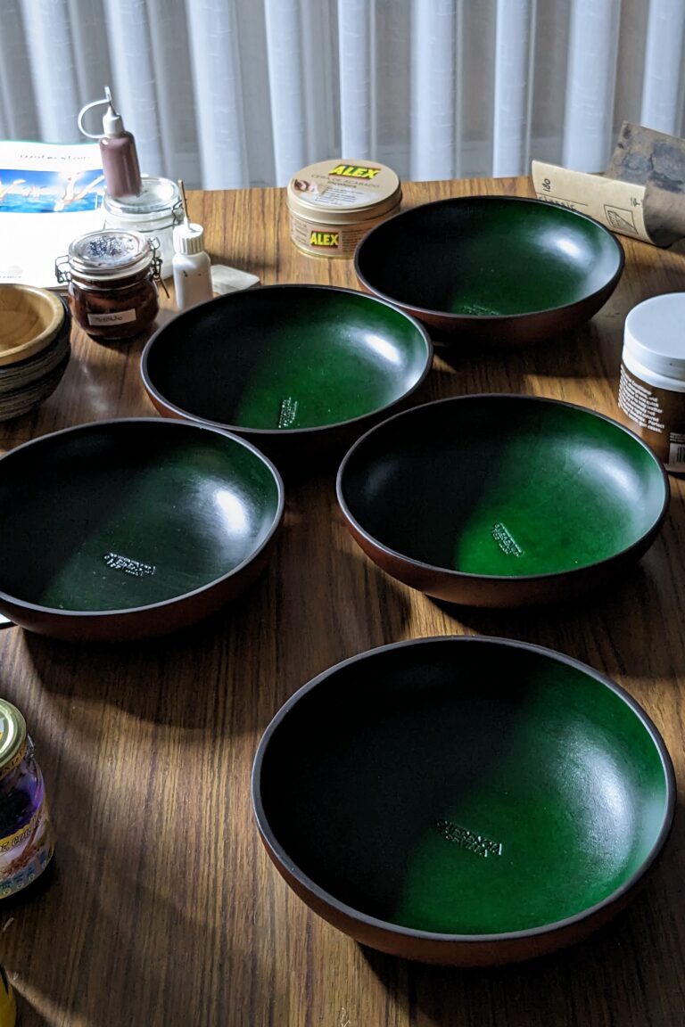 Cuencos de cuero teñidos de verde por dentro sobre la mesa del taller